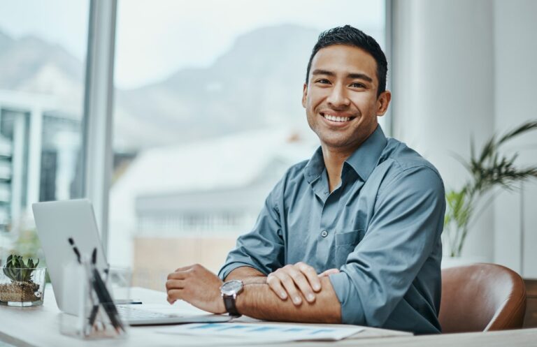 Young friendly looking man sitting at desk smiling