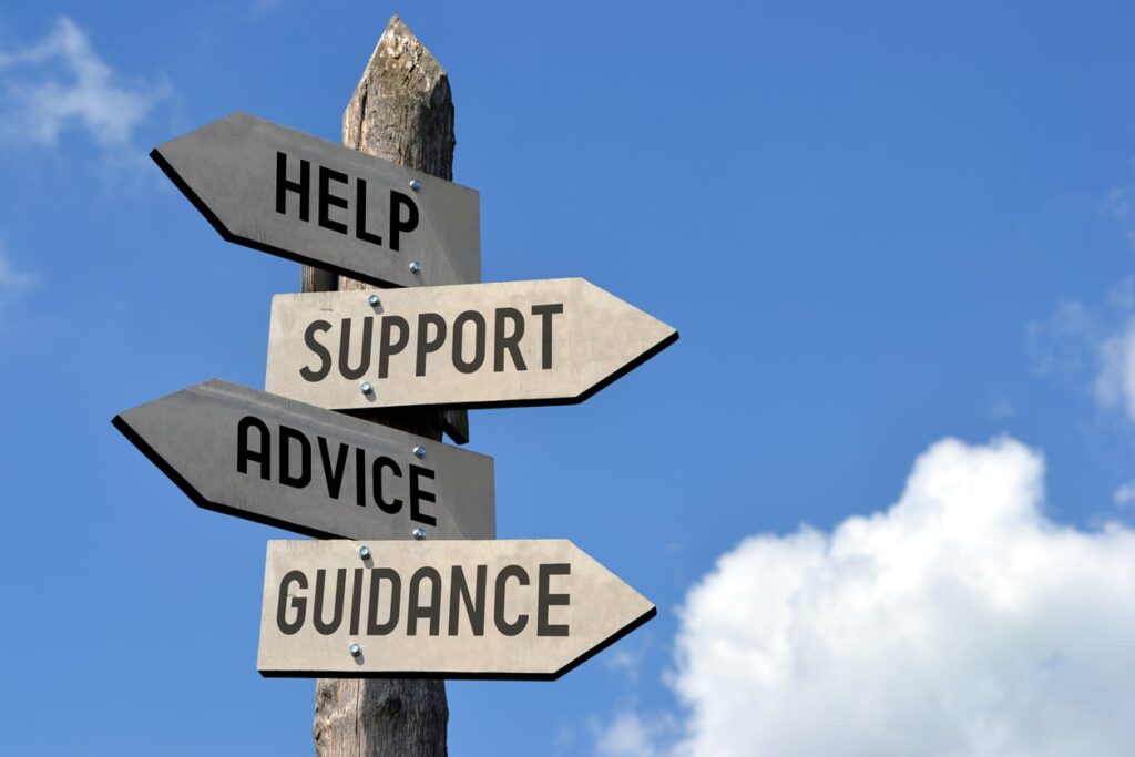 Sign post with arrows that say help, support, advice and guidance pointing in different directions.
