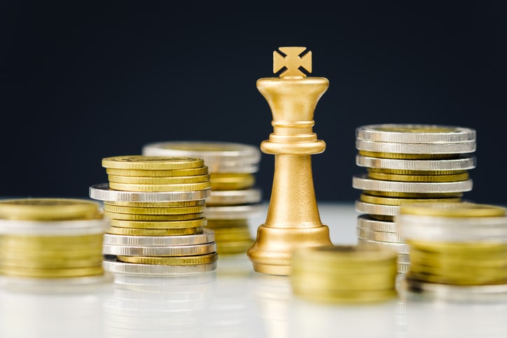 King chess piece surrounded by stacks of coins